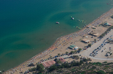 Popular Tsambika beach with azure sea and lots of sunbeds on the sandy shore top view (Rhodes, Greece)