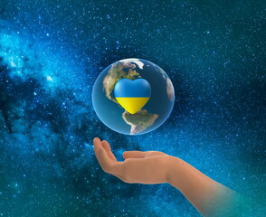  earth globe with Ukraine flag color blue and yellow in heart symbol in hands on front blue starry sky nebula hold world peace concept nature background