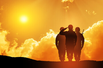 Silhouettes of soldiers saluting against the backdrop of a sunset. Greeting card for Veterans Day,...
