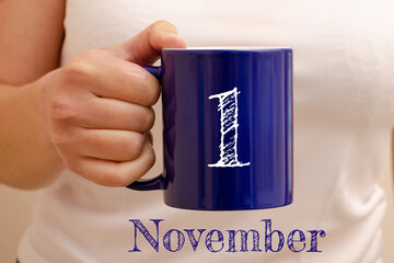 The inscription on the blue cup 1 november. Cup in female hand, business concept