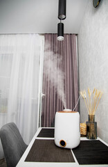 A modern humidifier sits on a table in a kitchen room. Humidification in the room, comfortable humidity and temperature