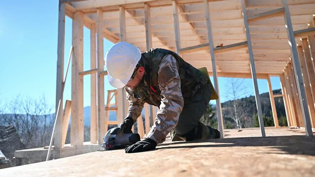 Carpenter using circular saw for cutting wooden OSB board. Man worker building wooden frame house. Carpentry concept.