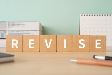 修正・改訂のイメージ｜「REVISE」と書かれた積み木が置かれたデスク