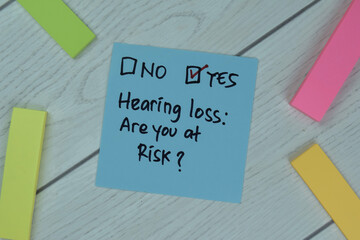 Concept Yes, Hearing loss: are you at risk? write on sticky notes isolated on Wooden Table.