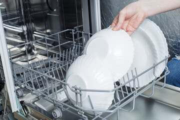 clean dishes in the dishwasher basket. Cleaning the house and washing dishes in the dishwasher.