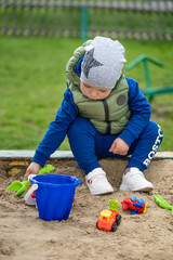 portrait of a 2 year old boy. Played in the playground in the sand on the street.