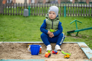 portrait of a 2 year old boy. Played in the playground in the sand on the street.