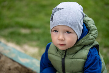portrait of a 2 year old boy. Played in the playground in the sand on the street.