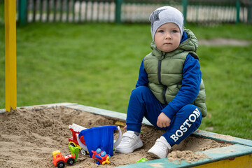 portrait of a 2 year old boy. Played in the playground in the sand on the street.