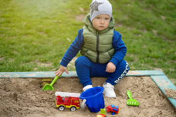 portrait of a 2 year old boy. Played in the playground in the sand on the street.