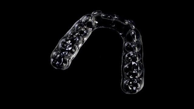 Invisible orthodontics cosmetic brackets on black background. Tooth aligners, for beautiful smile.