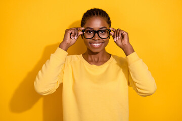 Portrait of attractive cheerful intellectual content girl touching specs isolated over bright yellow color background