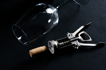 Corkscrew and wine glass on dark background