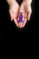 International Epilepsy Day. Adult hands holding purple ribbon on black background. Alzheimer's disease, Pancreatic cancer, Hodgkin's Lymphoma awareness