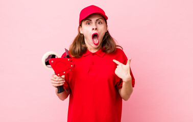 young pretty woman  looking shocked and surprised with mouth wide open, pointing to self. company...