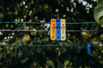 Clothespins on a clothesline in the garden. Colorful plastic clothespins on the hangers with blurred background.