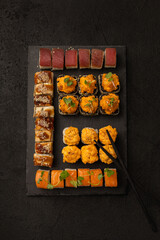 Set of various sushi rolls Japanese food on a black board for serving on a black background