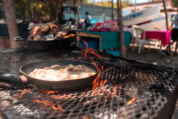 Close-up of fish croquettes frying in a pan over an artisan stove in a poor restaurant on the beach...