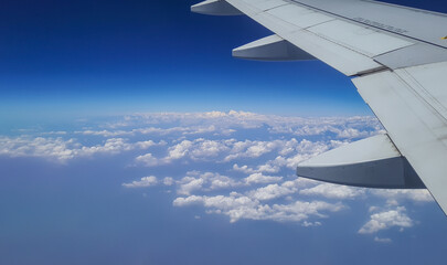 aircraft wings at mid air with low clouds and bright blue sky background