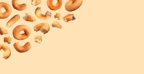 Creative food, baking layout. Fresh round wheat bagel with sesame seeds flying on beige background. Crispy bread, healthy organic food, traditional pastries, bakery product. Breakfast bagel