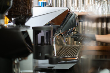 Close-up image of a coffee machine in a Cafe coffee shop or restaurant. Barista making hot coffee from a professional modern espresso brewing machine by a bottomless filter. Cafe Service Concept