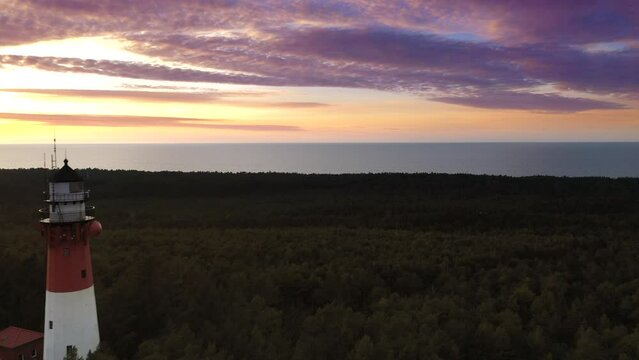 Aerial landscape of the sunset over the forest. Sea in the background. Orange sky and pastel clouds. 