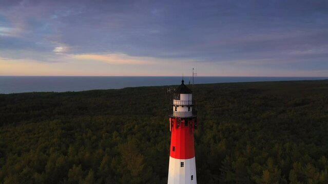 Aerial view of the lush green forest. Sea in the background. Flying next to the lighthouse.