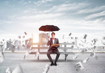 young businessman with an umbrella and a book