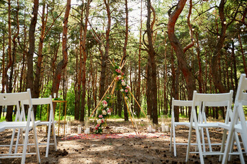 Beautiful bohemian tipi arch decoration on outdoor wedding ceremony venue in pine forest with...
