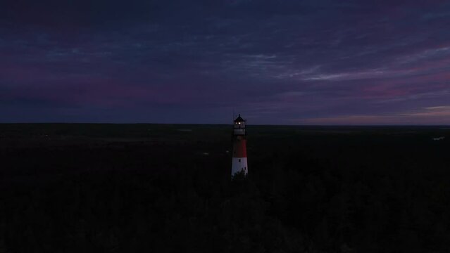 Aerial view of the lighthouse during sunset. Blue sky, orange sun, pastel pink clouds. Panoramic view.