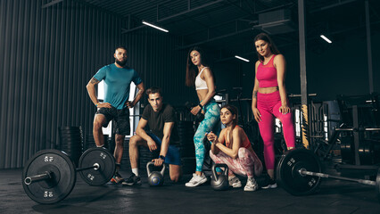 Group of young friends doing sports, training at gym indoors. Friends posing, resting after hard workout - obrazy, fototapety, plakaty