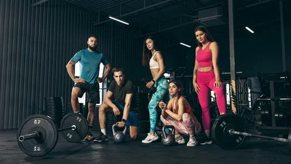 Acrylic prints Fitness Group of young friends doing sports, training at gym indoors. Friends posing, resting after hard workout