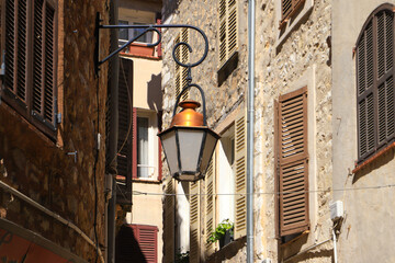 Fototapeta na wymiar A narrow alley with an old street lamp in the medieval town Vence - France