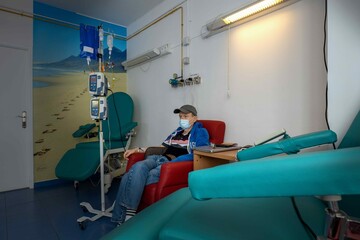 Man sitting in a chair, receives chemotherapy via infusion tubes