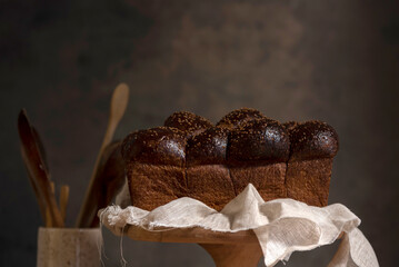 Homemade sourdough bread with seeds in different shapes and styles with olive oil on a still life table with a cloth rolling pin and window light