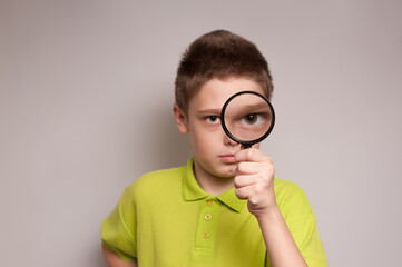 Fototapeta na wymiar An explorer boy holding a magnifying glass in front of his eyes