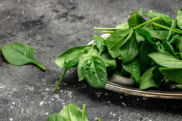 Close up Spinach. Raw organic fresh baby spinach leaves in a metal bowl on dark background. Food...