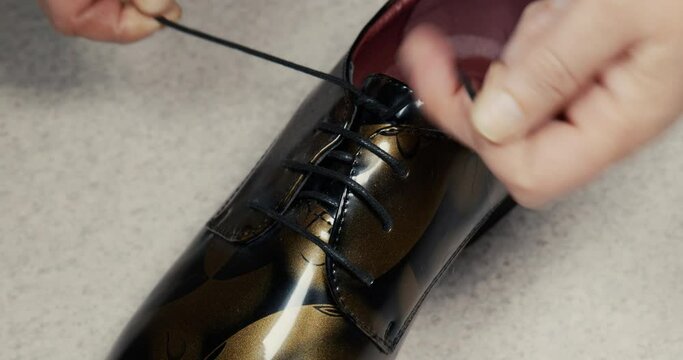 close up of hands tying shoelaces. tie his dress shoes