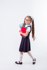 a little girl in glasses and a school uniform holds a book and a globe isolated on a white background