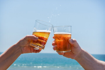 Toast at a beach bar with beer. Joy for the summer, sun and vacations