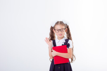 a little girl in glasses and a school uniform holds a book and a globe isolated on a white background