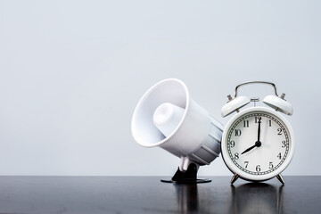 Alarm clock with megaphone on grey background with copy space.