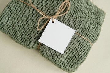 White empty square tag, card or label tied to a handmade knitted sweater, mockup for design...