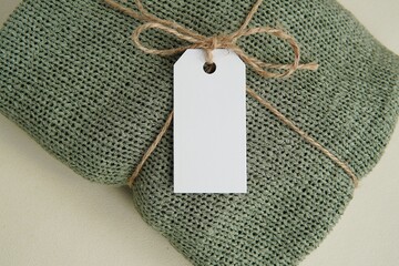 Rectangle white blank price tag, label with jute rope on handmade knitted sweater, tag mockup for...