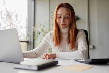 Woman with documents and laptop administrating a business, payments or taxes.