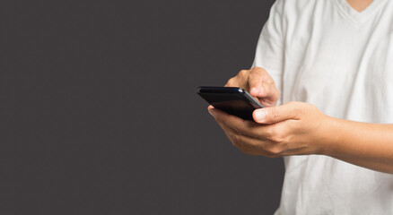 Close-up of hands using a mobile phone while standing over a gray background