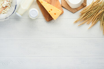 Shavuot jewish holiday celebration. Milk and cheese, ripe wheat and fruits, cream on white wooden background. Dairy products over white wooden background. Shavuot concept. Top view. Mock up.