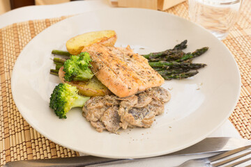 dish of fried river trout fillet with garnish of broccoli, asparagus sprouts and mushroom sauce