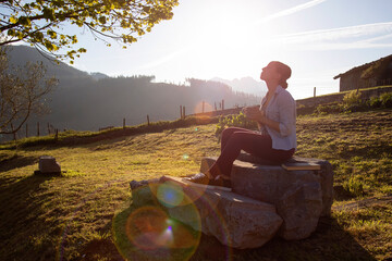 woman enjoying the aroma of freshly brewed coffee sitting on the backyard at dawn ready to read a book and enjoy the vacation.