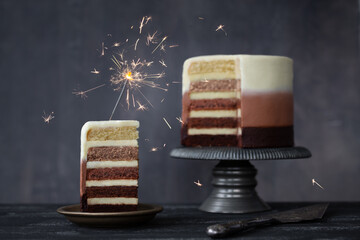 Slice of chocolate ombre birthday cake with celebration sparkler